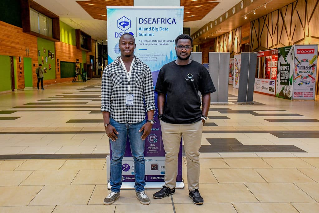 Two attendees beside the summit banner in the concourse