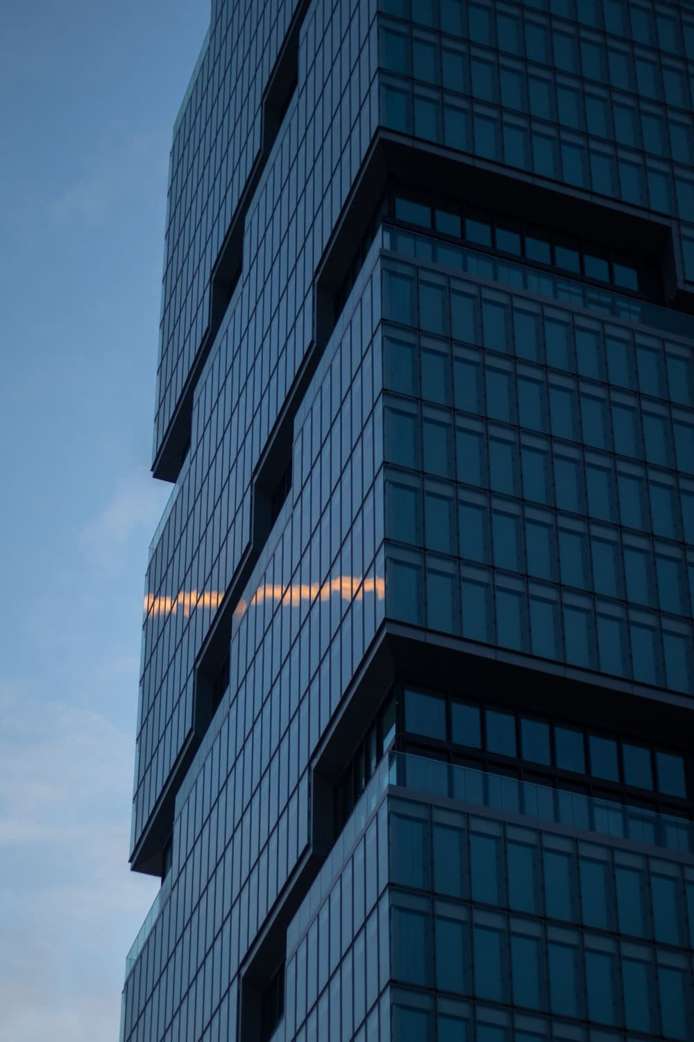 A modern glass office tower against an evening sky