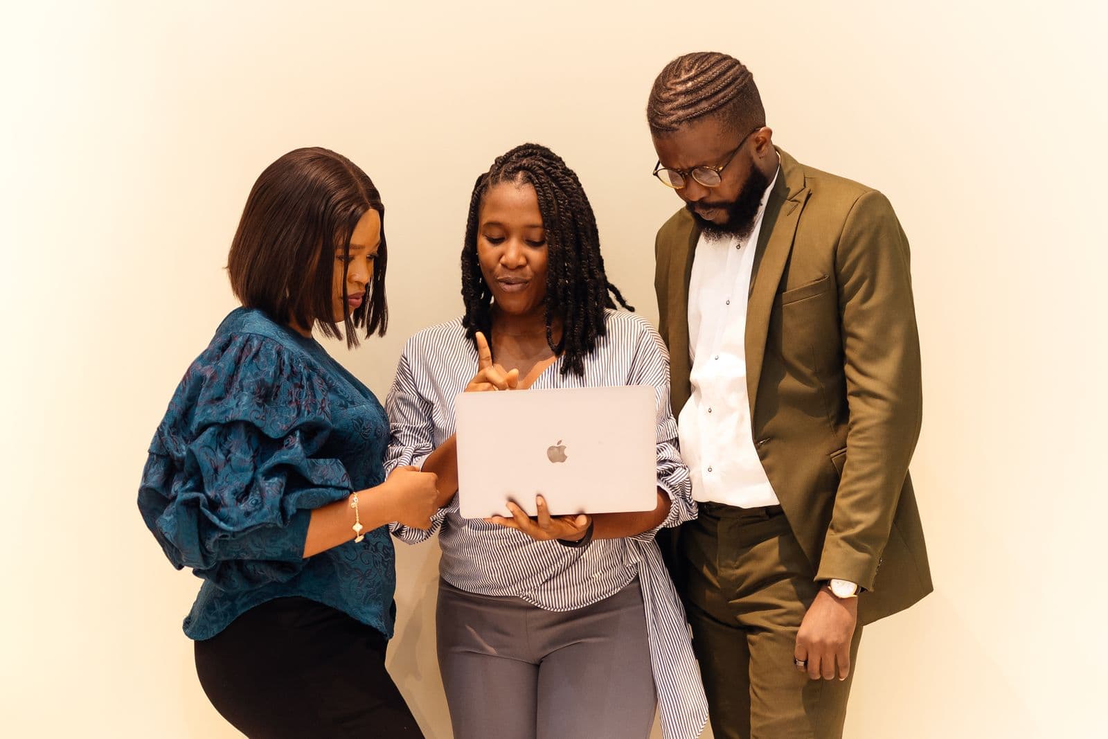 Three African data professionals gathered around a laptop, reviewing work together